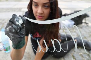 Die Nürnberger Designerin und Typographie-Künstlerin Hannah Rabenstein schreibt am 10.08.2017 in Nürnberg (Bayern) mit weißer Acrylfarbe auf eine Glasscheibe. Rabenstein gehört zu den Pionieren des neuen Gestaltungstrends Handlettering. Hinter dem englischen Begriff verbirgt sich die Lust am Zeichnen und Malen von Buchstaben, die Kunst der Schönschrift. (zu dpa-Korr "Stifte-Hersteller jubeln: Handlettering folgt Ausmaltrend" vom 18.08.2017) Foto: Daniel Karmann/dpa +++(c) dpa - Bildfunk+++